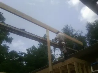 Carpenter setting a ridge beam over a new addition frame — Ice Dam Removal by Roofing Brothers in Accokeek