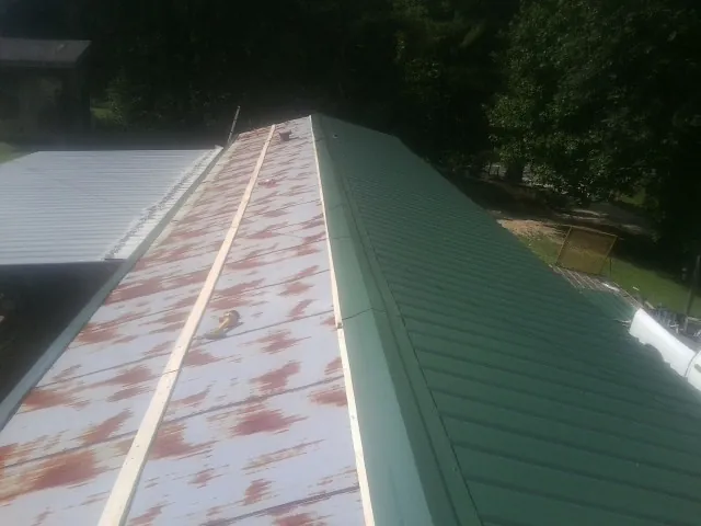 Old rusted panels beside newly installed green metal roofing — Wind Damage Roof Repair by Roofing Brothers in Accokeek