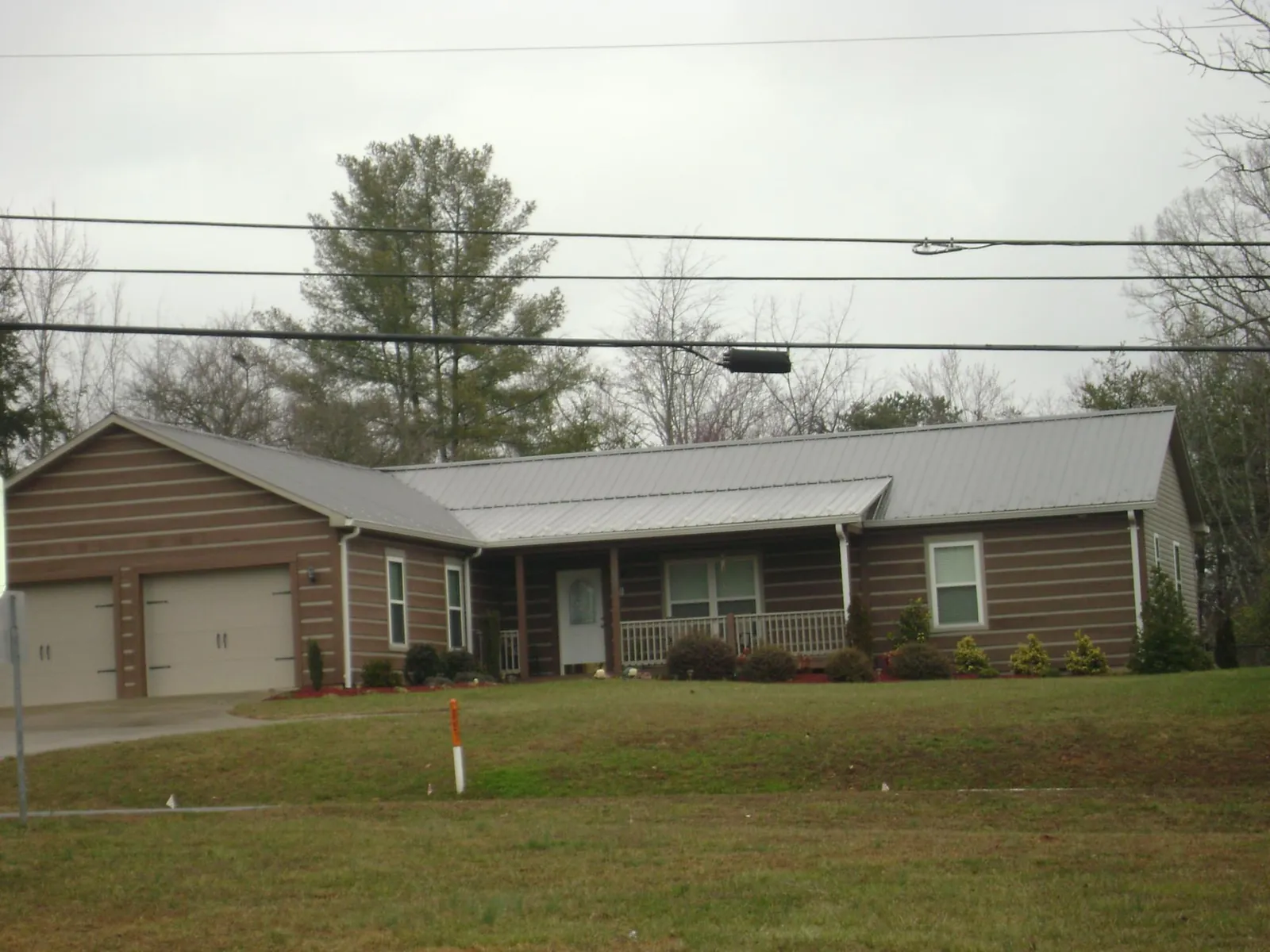 Gray metal roof on a log sided ranch home with a front porch in Accokeek