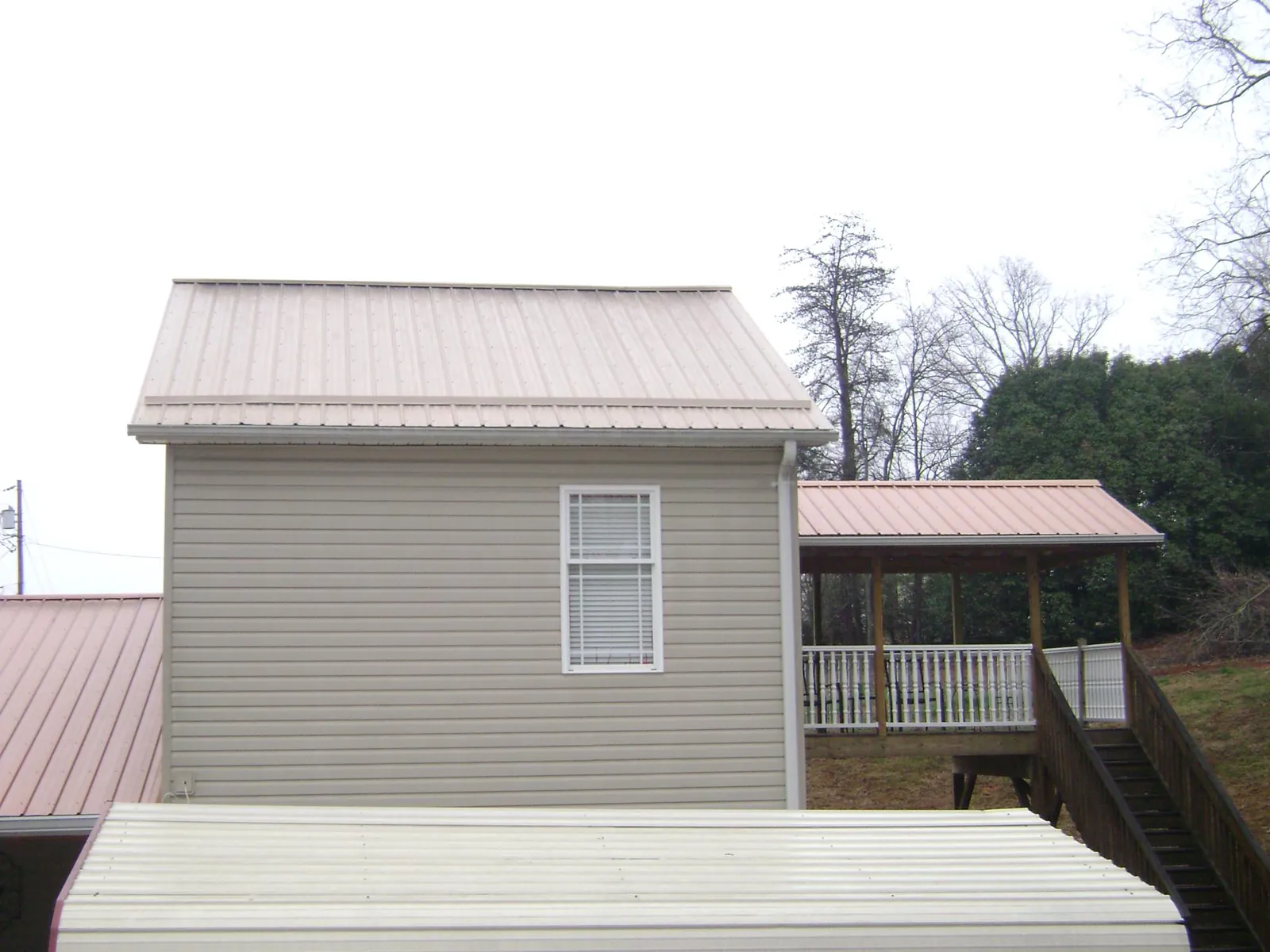 Tan metal roofs on a two story addition and attached porch, from a Roof Replacement job in Accokeek