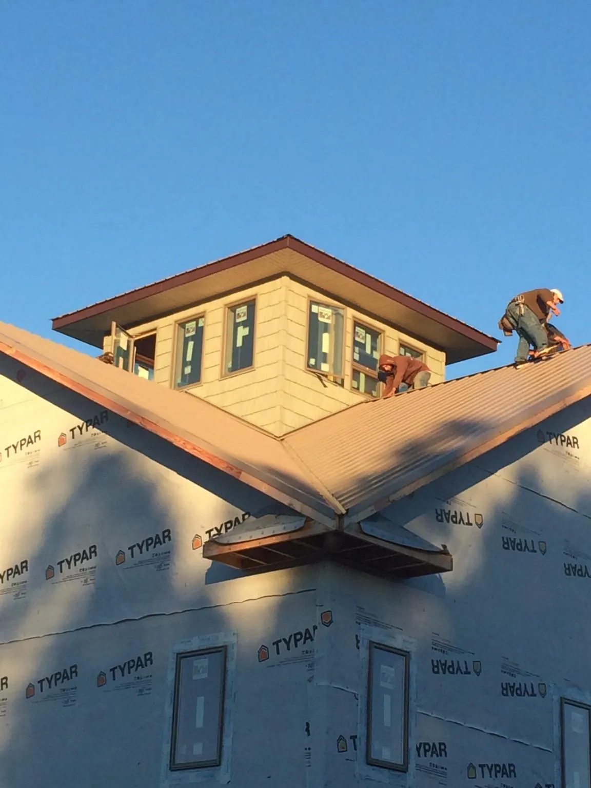 Roofers working around a rooftop cupola on a new metal roof at sunset — Roof Waterproofing in Accokeek by Roofing Brothers